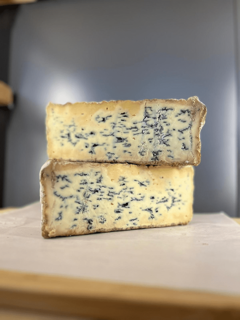 Two blocks of pevensey blue cheese stacked on top of eachother.